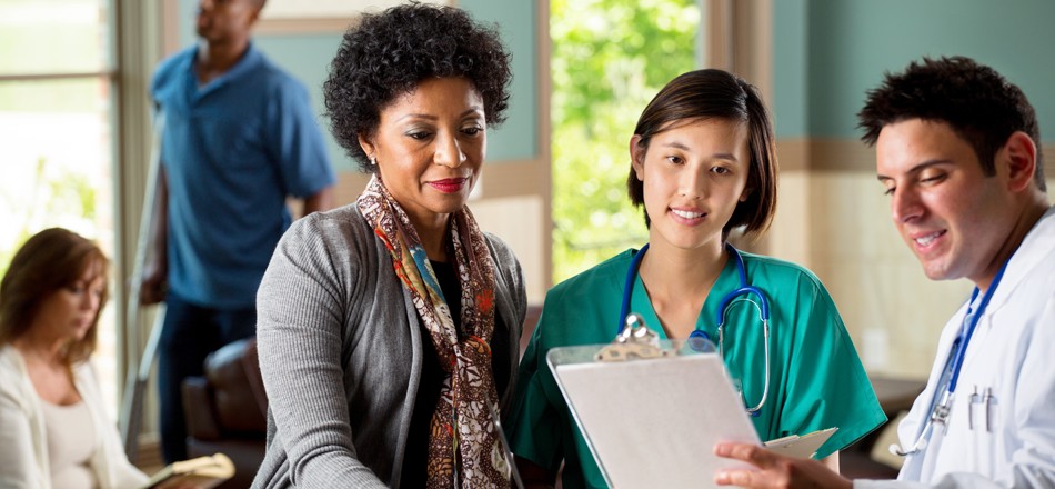 A businesswoman talks with a doctor who is displaying information on a board