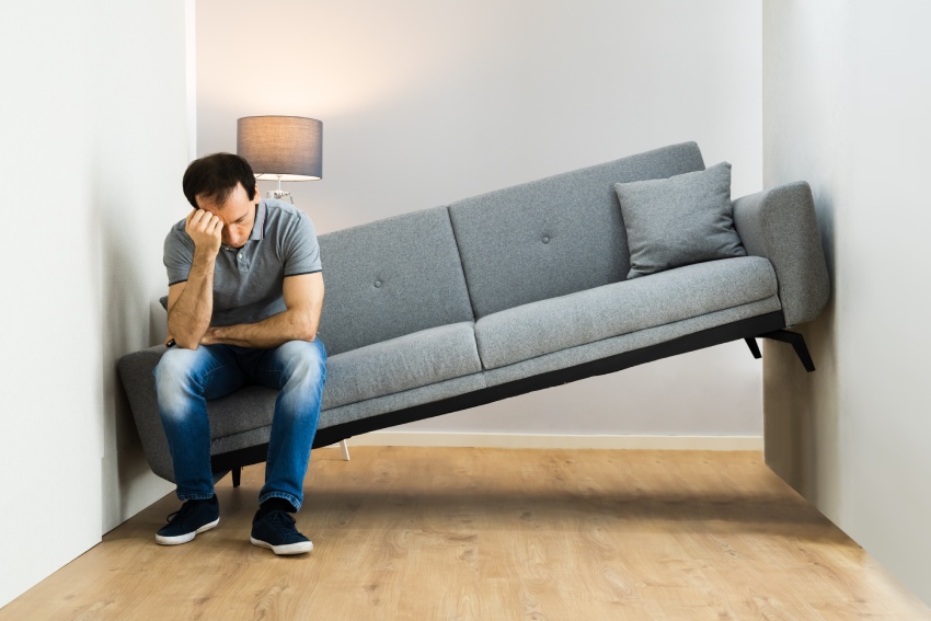 Man sitting with sofa stuck between walls
