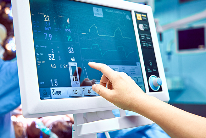 A person pointing at a monitor in a hospital