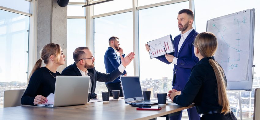 Successful meeting of business people, discussing new business ideas, using diagrams, sitting together. Modern office background. Meeting of business partners at the conference on business development