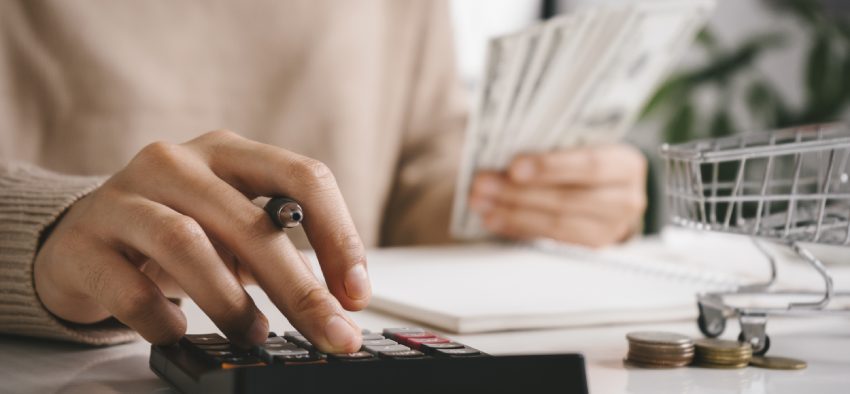 Woman counting and calculate cost money with calculator at home. Budget of disadvantaged and low income family for rising food and grocery store prices and expensive daily consumer goods concept.
