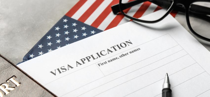 Passport, American flag and visa application form on table. Immigration to USA