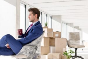 a man in a suit sitting on a chair with a cup of coffee