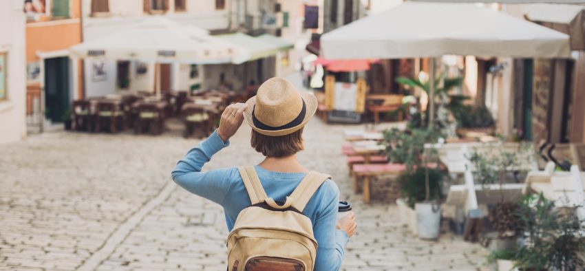 Tourist girl walking in the city during vacation. Cheerful woman traveling abroad in summer. Travel and active lifestyle concept