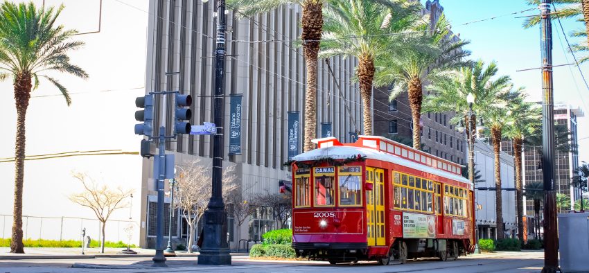 New Orleans, Louisiana United States - December 25 2020: a red trolley downtown with palm trees lining the tracks