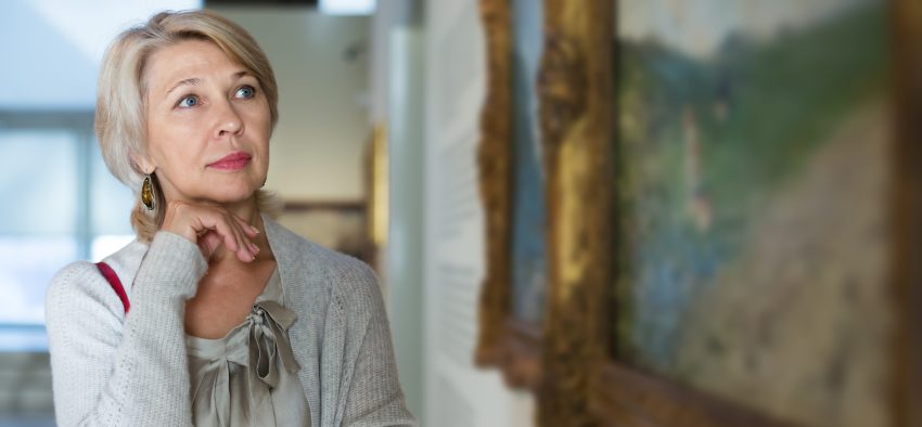 Portrait of senior woman near picture collection in the museum