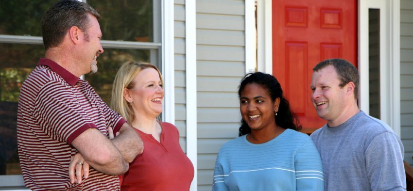 Two happy couples standing outside a new home