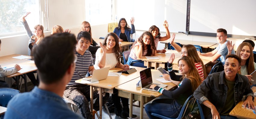 Rear View Of Male High School Teacher Standing At Front Of Class Teaching Lesson