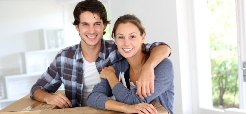Smiling couple leaning on boxes in new home