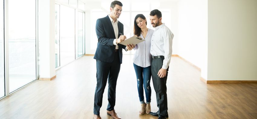 Mid adult realtor explaining agreement to couple in new apartment