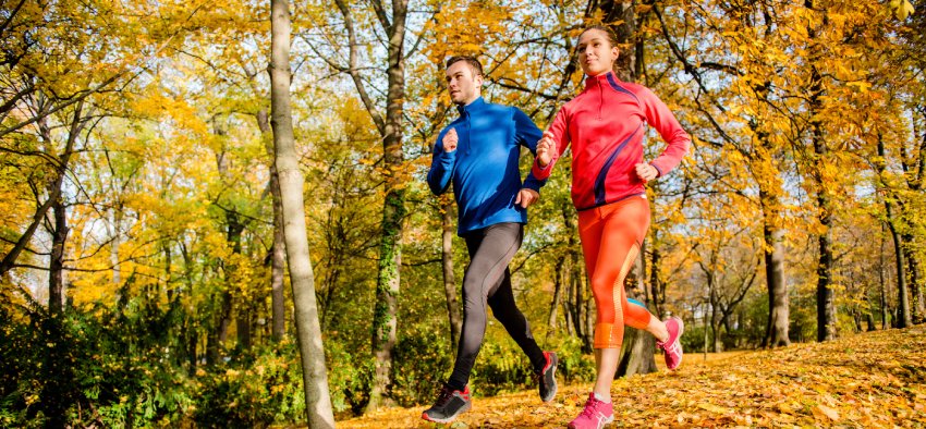 Young couple jogging together in fallen autumn leaves