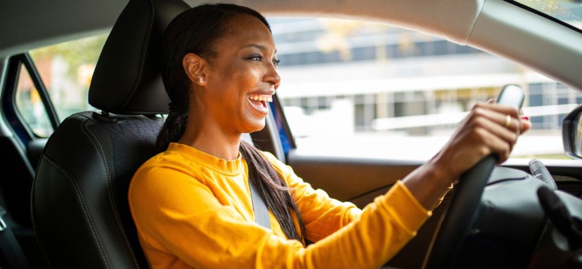 Portrait of joyful young african american woman driving a car